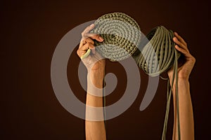 Closeup female hands holding hank of green ribbon yarn and knitting decor or clothes isolated