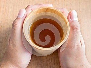 Closeup of female hands holding wood cup of Organic Jasmine Tea