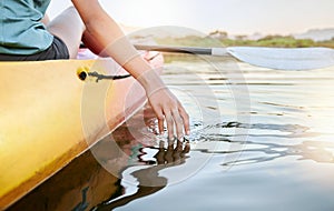 Closeup of female hands kayaking and feeling lake water during the day. Active young woman enjoying water activity while