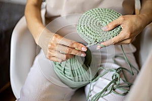 Closeup female hands knitting interior decor basket use green ribbon yarn and crochet needle