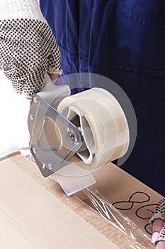 Closeup of Female Hands Packing Cardboard Box Indoors Unsing A Tape-Machine