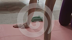 Closeup of female hands on a pink rug for yoga. Concept of domestic training. On the floor lie races and rope