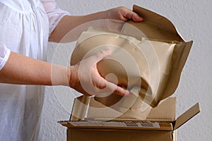 closeup of female hands take out package from open cardboard box, bundle of collagen, postal box with wrapping paper, parcel,