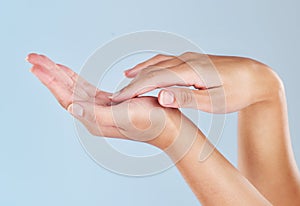 Closeup of female hands touching her palm. One woman with soft, flawless, moisturized skin isolated on a blue background