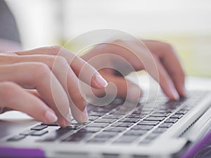 Closeup female hands typing on laptop keyboard.