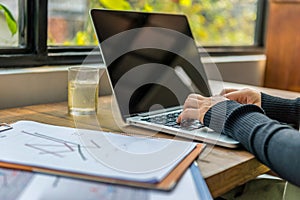 Closeup of female hands typing laptop keyboard next to window