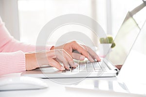 Closeup female hands typing on laptop keyboard. Woman working at home office