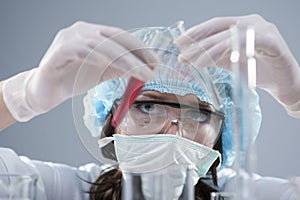 Closeup of Female Laboratory Staff Conducting Experiment with Two Liquid Specimens in Flasks In Laboratory