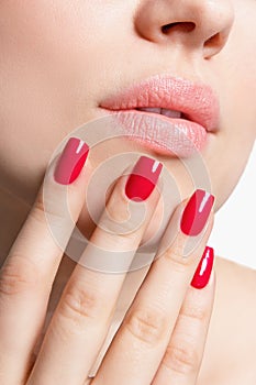 Closeup of female lips and hand with red nail polish.