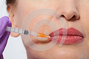 Closeup of female mouth and lips with botox and syringe needle in lip. Selective focus and macro face.