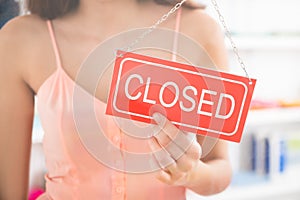 Owner Holding Closed Sign In Clothing Store