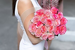 Closeup female person hand holding big bunch of fresh natural tender pink roses at date on city street outdoors. Happy