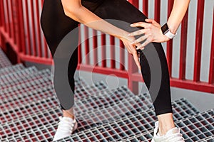 Closeup of female runner in sportswear holding painful knee while climbing stairs, touching leg suffering muscle strain