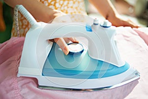 Closeup on female setting ironing temperature