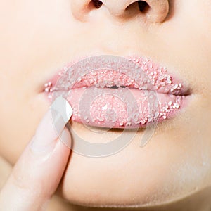 Closeup on female sweet sugary lips with finger nicely manicured