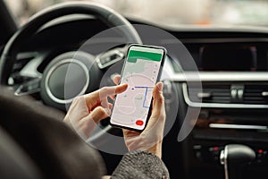 Closeup of female traveler using cell phone with gps navigation app on screen while sitting in car