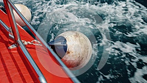 Closeup of fenders and buoys hanging on the side of red rescue boat sailing through cold northern sea