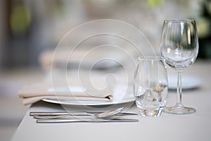 Closeup of a festive table with white dishes and glasses, blurred background, just married