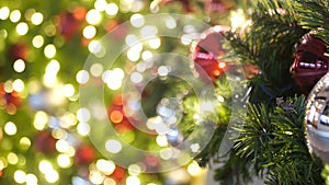 Closeup of Festively Decorated Outdoor Christmas tree with bright red balls on blurred sparkling fairy background