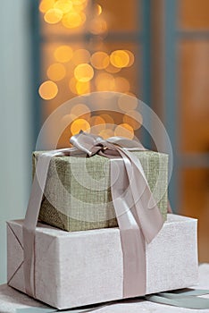 Closeup of festively wrapped gift boxes on a Christmas background of sparkling lights, a magical New Year\'s background.