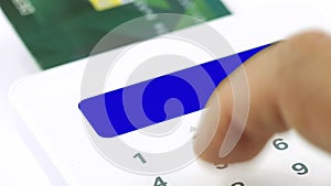 Closeup finger entering pin personal identification number for electronic purchasing by credit or debit card blue screen display