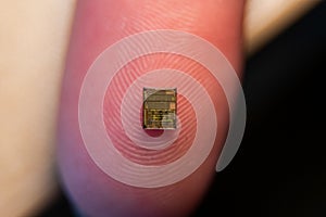 Closeup of a finger holding a microelectronic chip