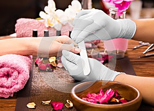 Closeup finger nail care by manicure specialist in beauty salon.