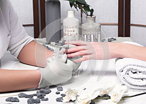 Closeup finger nail care by manicure specialist in beauty salon.