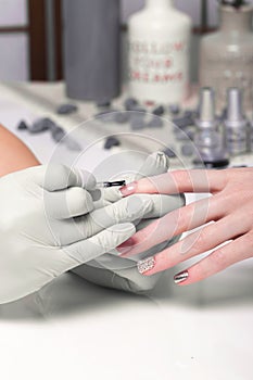 Closeup finger nail care by manicure specialist in beauty salon.