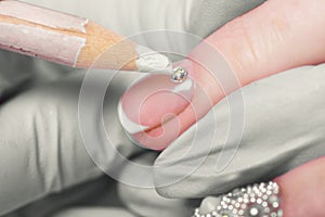 Closeup finger nail care by manicure specialist in beauty salon.