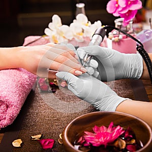 Closeup finger nail care by manicure specialist in beauty salon. photo