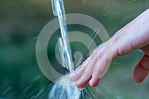 Closeup of fingers on the flowing water from the faucet