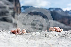 Closeup of fingers gripping a rock.