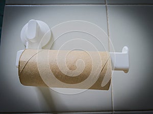 Closeup of finished toilet paper roll in bathroom. Empty roll on toilet paper holder with white wall background. Vintage, lowkey