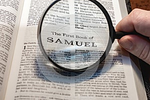 closeup of the first book of Samuel from Bible or Torah using a magnifying glass to enlarge print.