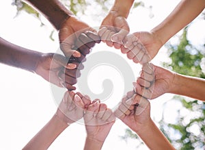 Closeup of fists in a circle outside in nature. Diverse group of peoples fists touching. Multiethnic people with their