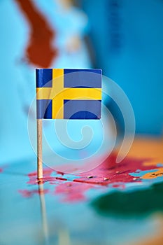 Closeup of a flag of Sweden with a small stick on the map