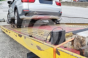 Closeup of flat bed tow truck attempt to tow and rescue broken down car witg cable