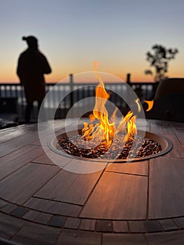 Closeup of a flickering fire pit on a wooden deck with a blurry background