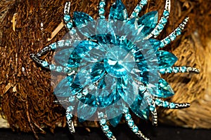 Closeup of a floral brooch embellished with blue gems and diamond stones
