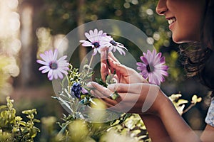 Closeup, flowers and woman with plants in nursery, smelling and sunshine with smile, spring and nature. Person, outdoor