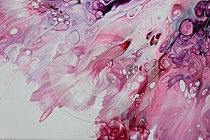 Closeup of a flowing abstract acrylic pour painting in shades of pink and white.