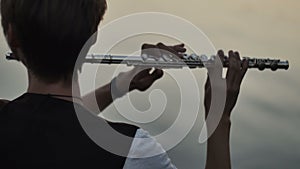 Closeup of flutist playing in the sunset near water