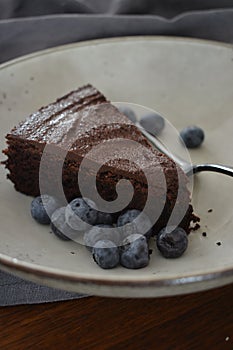 Closeup fo a piece of delicious chocolate cake with blueberries on a plate