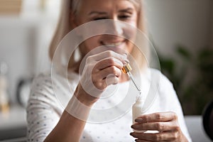 Closeup focus on aged woman hands holding face serum bottle