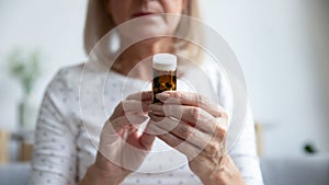 Closeup focus on elderly woman hands holding bottle of pills
