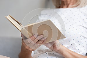 Closeup focus on middle-aged female hands holding opened book