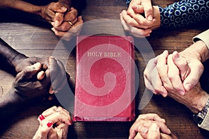 Closeup of folded hands and Holy Bible Diverse religious shoot