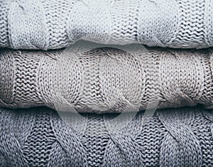 Closeup on folded knitware sweaters, pastel grey colors