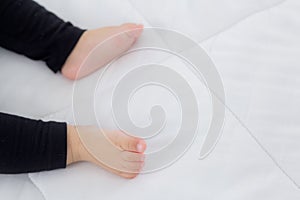 Closeup foot of asian little baby girl sleeping on bed in the bedroom at home, newborn napping with cozy and relax.